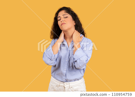 Sad tired latin young woman with long hair, massages neck with hands 110954759