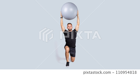 Glad strong muscular millennial european guy with beard, make exercises with fit ball for hands, enjoy workout 110954818