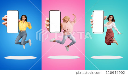 Happy millennial european women show phone with empty screen, peace sign, jump at platform 110954902