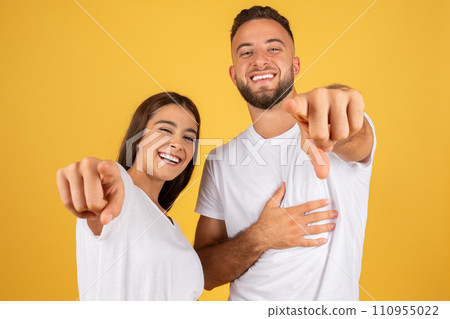 Smiling confident young european man and lady in white t-shirts point finger at camera Smiling confident young european man and lady in white t-shirts point finger at camera 110955022