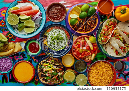 A colorful and appetizing top view of Mexican festive food for Independence Day, featuring chili, cilantro, tacos, burritos, chalupas, pozole, tamales, and chicken with mole poblano sauce. 110955175