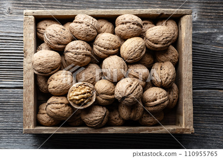 Walnut nuts in a wooden box on old wooden table Walnut nuts in a wooden box on old wooden table 110955765