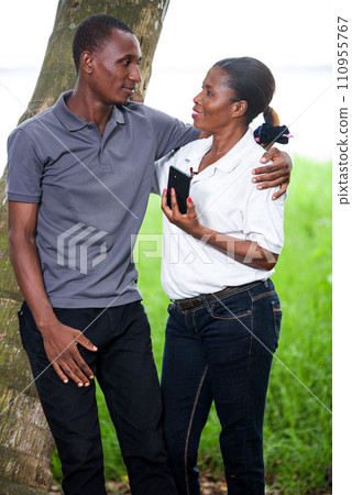 couple in love and happy leaning on a tree in a park 110955767