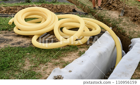 A worker carries a yellow perforated drainage pipe. Groundwater drainage works in the field A worker carries a yellow perforated drainage pipe. Groundwater drainage works in the field 110956159