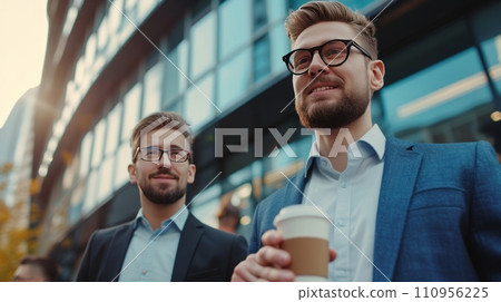 Two young handsome businessmen drinking coffee at a meeting against the backdrop of a modern  business center 110956225