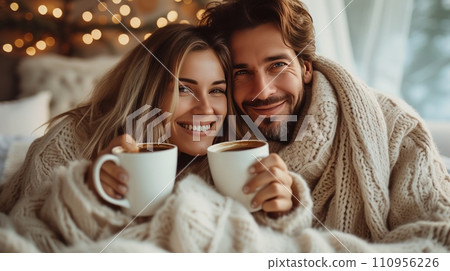 Young and happy couple in pajamas drinking coffee in bed Young and happy couple in pajamas drinking coffee in bed 110956226