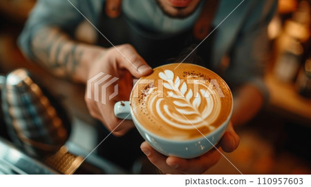 A young handsome barista in a coffee shop makes a beautiful cappuccino with a pattern of a leaf shape 110957603