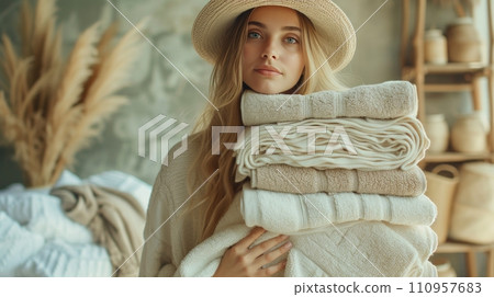 A young woman carries a large stack of complex towels in her hands A young woman carries a large stack of complex towels in her hands 110957683
