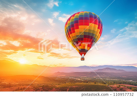 Vibrant hot air balloon floats over scenic mountains at sunset. 110957732