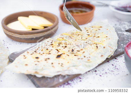 Front view of chef, cook pouring honey with spoon on wrapped pita and taco lying on wooden board. Concept of fast food. 110958332