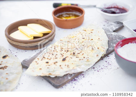 Front view of stylish wooden board dusted with flour with grilled, wrapped pita, taco lying outdoor. Concept of street food. 110958342