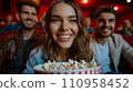 Beautiful young couple sitting in a cinema with a big bucket of popcorn 110958452