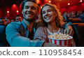 Beautiful young couple sitting in a cinema with a big bucket of popcorn 110958454