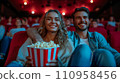 Beautiful young couple sitting in a cinema with a big bucket of popcorn 110958456