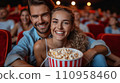 Beautiful young couple sitting in a cinema with a big bucket of popcorn 110958460
