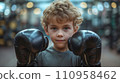 Boy trying on big boxing gloves in the gym 110958462