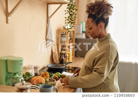 Side view of pregnant young African American woman preparing meal on kitchen table from fresh ingredients Side view of pregnant young African American woman preparing meal on kitchen table from fresh ingredients 110958603
