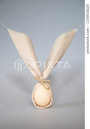 egg wrapped in easter bunny shaped napkin egg wrapped in easter bunny shaped napkin 110958826