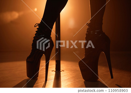 Close up shot of black leather platform boots on feet of unrecognizable exotic pole dancer in backlight 110958903
