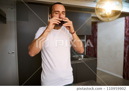 Handsome young man in white t-shirt, enjoying his morning coffee at home 110959902