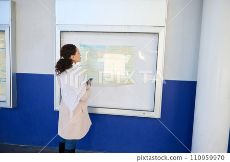 Young woman commuter watching board with train schedules at a railway station. People. Railroad trip. Copy ad space Young woman commuter watching board with train schedules at a railway station. People. Railroad trip. Copy ad space 110959970