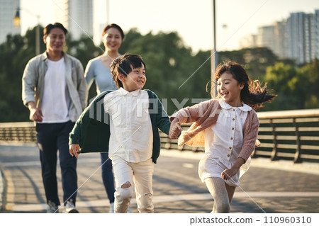 happy asian family with two children walking on pedestrian bridge in city park happy asian family with two children walking on pedestrian bridge in city park 110960310