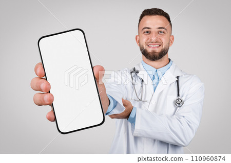 Man doctor with big phone, blank screen on grey background Man doctor with big phone, blank screen on grey background 110960874
