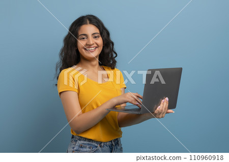 Portrait of confident young indian woman holding and using laptop 110960918