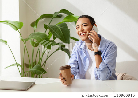 Smiling young lady with short hair, with smartwatch holding coffee cup in hand 110960919