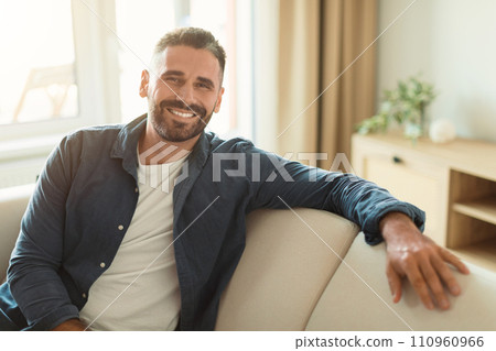 Happy middle aged guy sitting on cozy couch at home 110960966