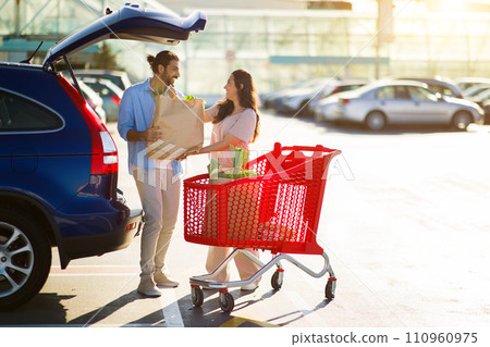 Arab couple by car with grocery bag and cart 110960975