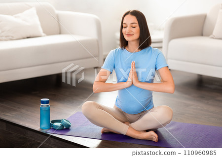 Calm pregnant lady practices pilates and yoga meditating at home 110960985
