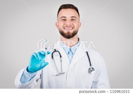 Cheerful male doctor holding a syringe, ready for vaccination 110961031