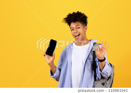 Happy black male student showing phone with blank screen and okay sign 110961041