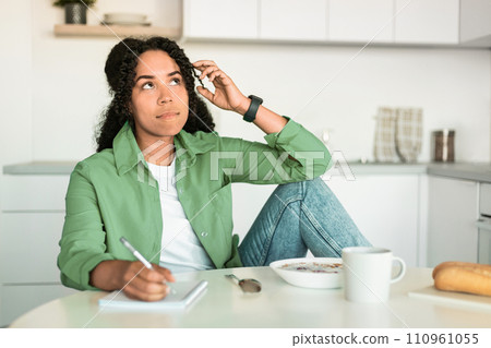 African American Lady Having Breakfast Writing Notes In Modern Kitchen 110961055