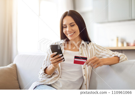 Happy Young Woman Shopping Online With Smartphone And Credit Card At Home Happy Young Woman Shopping Online With Smartphone And Credit Card At Home 110961066