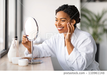 Beautiful Black Lady Looking In Mirror And Making Skincare Routine At Home 110961148