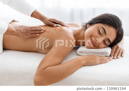 Relaxed indian lady having skin scrubbing procedure at spa salon 110961194