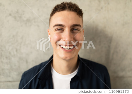 Smiling attractive young european guy in casual, wireless headphones enjoy lifestyle, listen music 110961373