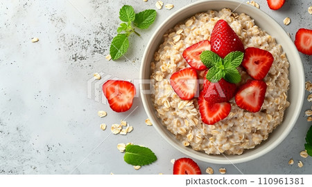 Nutritious oatmeal porridge bowl with strawberries on white tabletop  a healthy breakfast option. 110961381