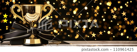 Golden championship cup trophy with magical defocused background and celebration confetti 110961425