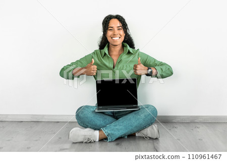 Black woman showing laptop blank screen gives thumbs up indoor 110961467