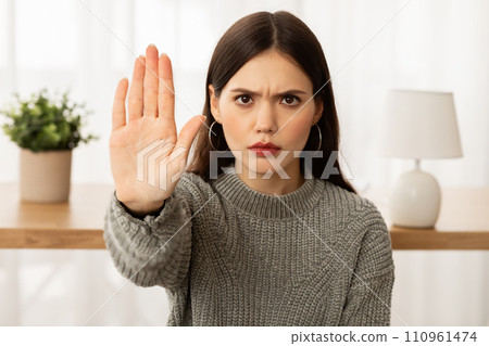 Angry young brunette woman showing stop gesture at camera 110961474