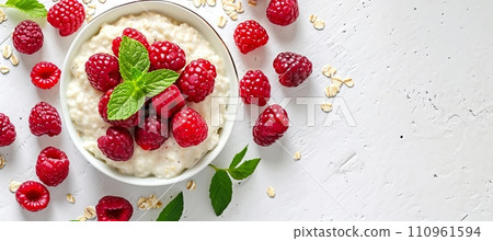 Top view of healthy oatmeal porridge with berries in bowl on white table, copy space for text 110961594