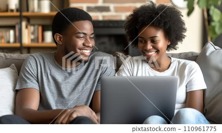 Happy multiracial couple on sofa, watching something interesting on laptop at home Happy multiracial couple on sofa, watching something interesting on laptop at home 110961775