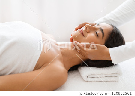 Relaxed young indian woman enjoying face lifting massage in spa 110962561