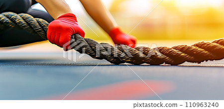 Young man exercising with battle rope at gym, fitness workout concept with copy space 110963240