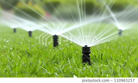 Automatic garden watering systems with sprinklers for lush green lawn in beautiful garden Automatic garden watering systems with sprinklers for lush green lawn in beautiful garden 110963257