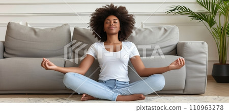 Serene young woman practicing meditation at home to promote mental well being and alleviate stress 110963278