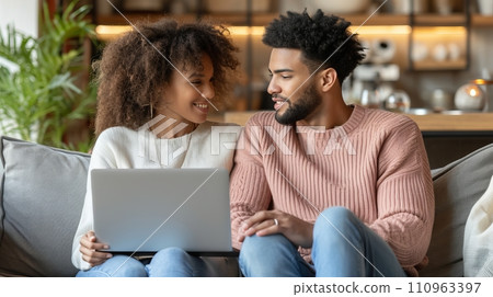 Multiracial young couple enjoying quality time together while watching laptop on home sofa 110963397